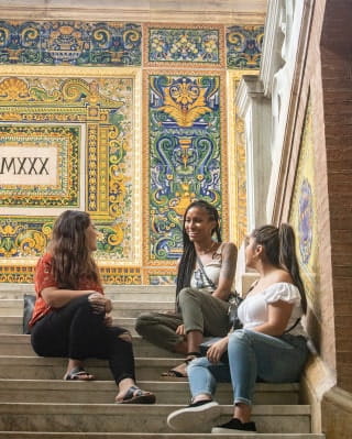 Three girls sitting on steps with tile walls in the background